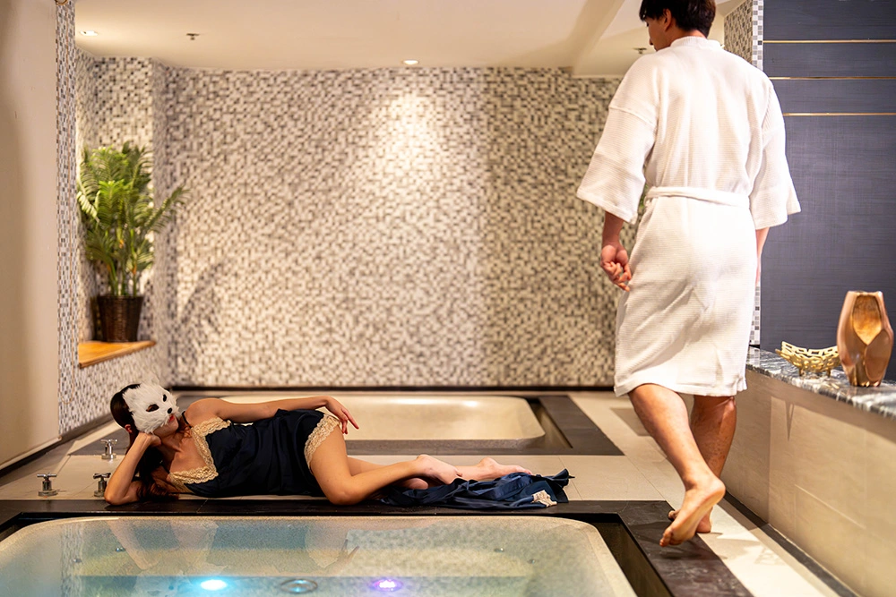A model relaxing beside a bathtub at Tara Bangkok Soapy Massage private suite